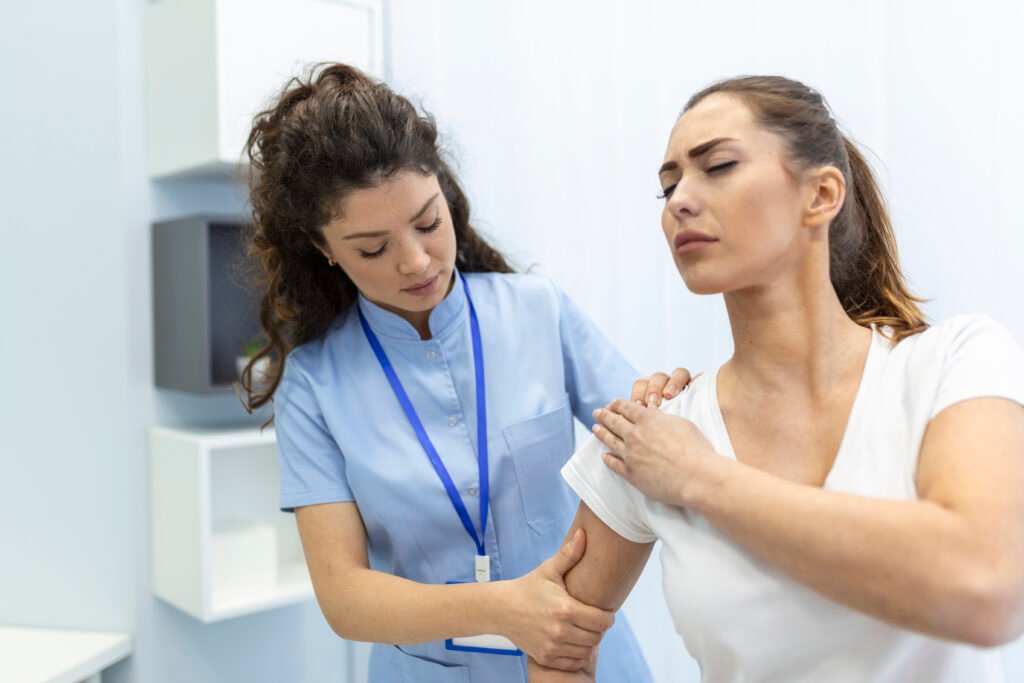 Woman doctor osteopath in medical uniform fixing woman patients shoulder and back joints in manual therapy clinic during visit. Professional osteopath during work with patient concept